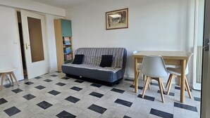 A room with a sofa, a dining table with chairs, a framed picture on the wall, and a tiled floor. - Vue MER bleu sea beach Holidays tramway (Nice)