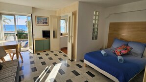 A room with a bed, a desk, a TV, and a balcony with a view of the sea. - Vue MER bleu sea beach Holidays tramway (Nice)