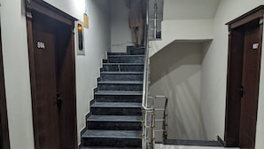 Un escalier avec des marches en marbre noir et une rampe métallique, flanqué de portes en bois portant les numéros 804 et 807.