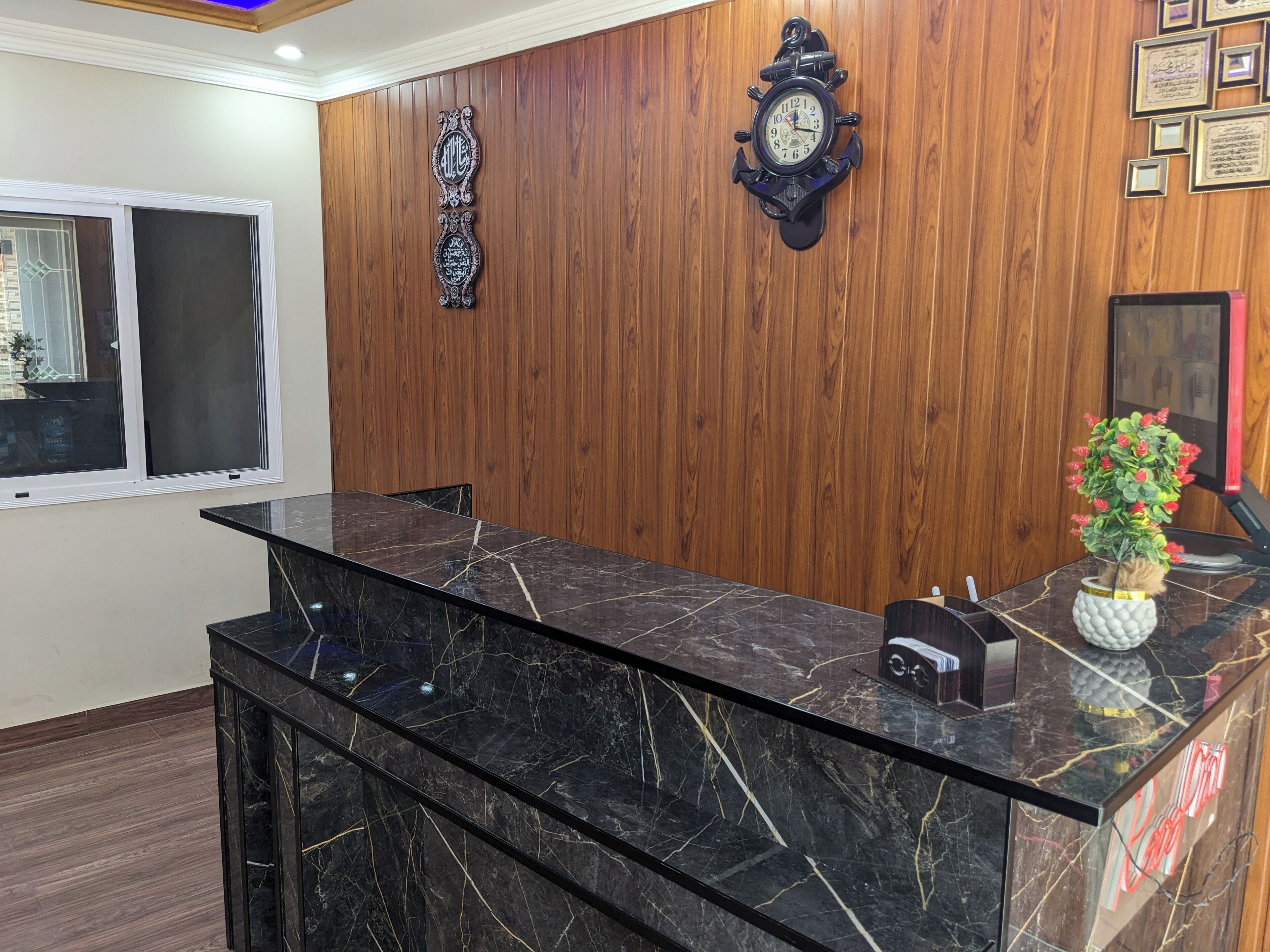 A reception desk with a marble top, a wall-mounted clock, and a decorative wall piece.