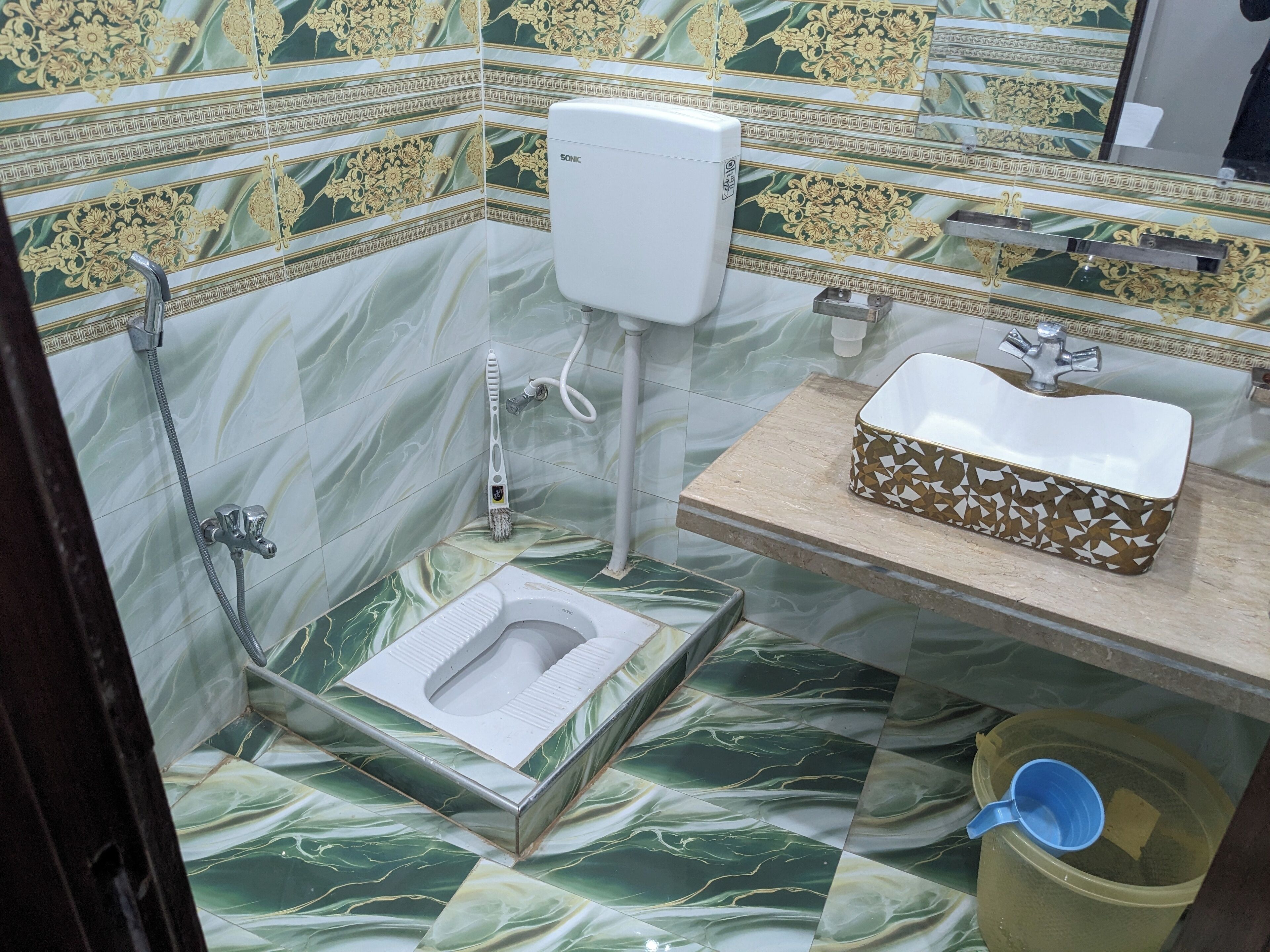 A bathroom with a toilet, a sink, a shower, and a toilet paper holder.
