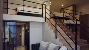 A modern living space with a staircase, a sofa, and a glass door leading to another room. - Cozy amazing view loft condo in Asoke Rama9 next to MRT (Huai Khwang)