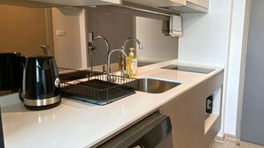 A modern kitchen with a built-in dishwasher, a kettle, and a sink with a soap dispenser. - Cozy amazing view loft condo in Asoke Rama9 next to MRT (Huai Khwang)