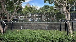 Un área de piscina tranquila al aire libre, con vista despejada a un edificio moderno al fondo.