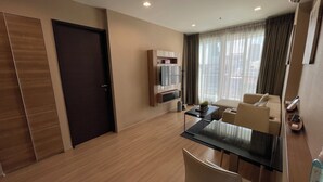 Una sala de estar moderna con una mesa de vidrio, un sofá y un televisor montado en la pared.