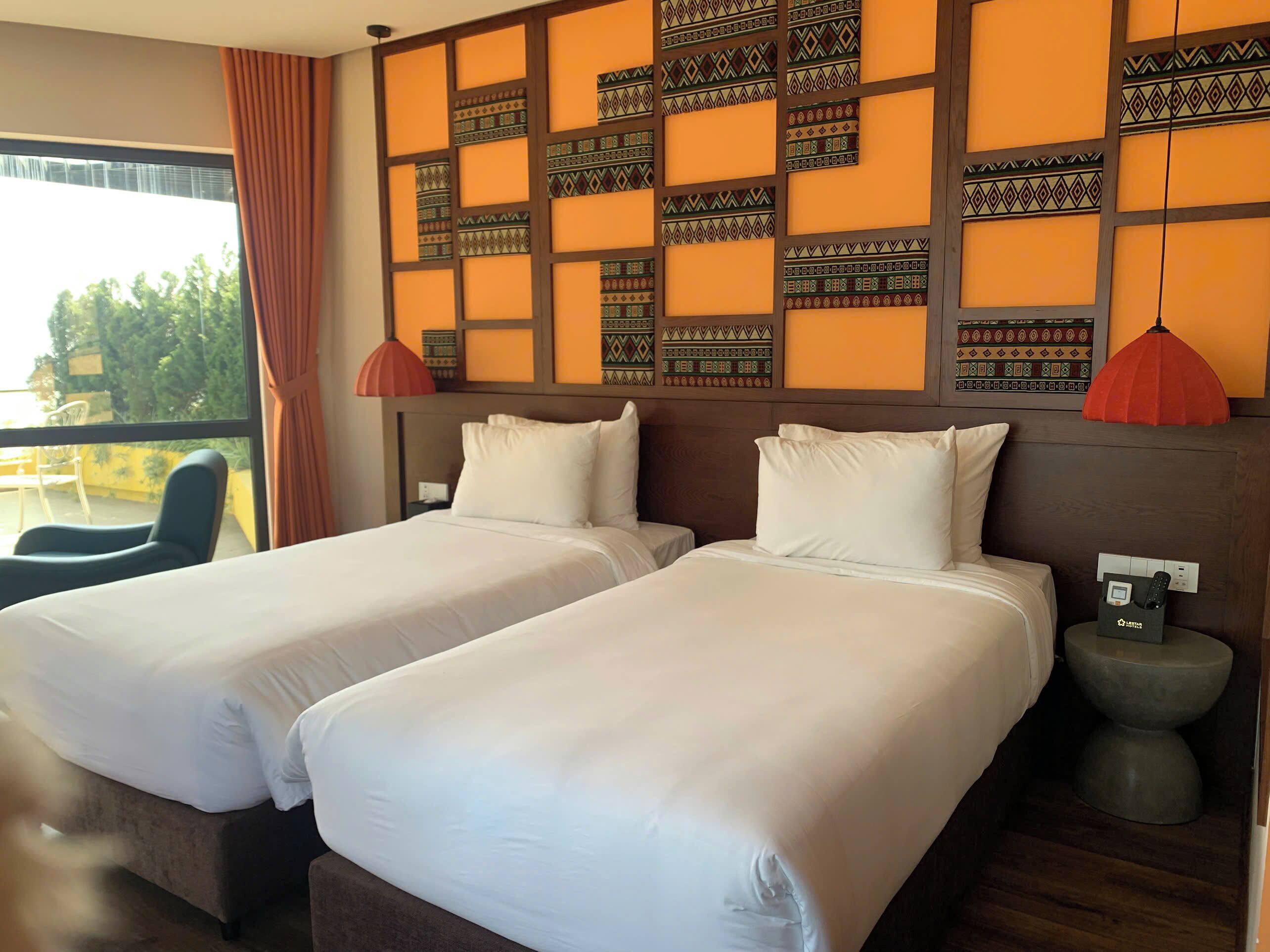 A hotel room with two beds, a view of the outdoors, and a modern design with patterned wall panels.