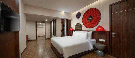 Una habitación de hotel moderna con una cama grande, suelo de madera, televisión y un adorno rojo en la pared.