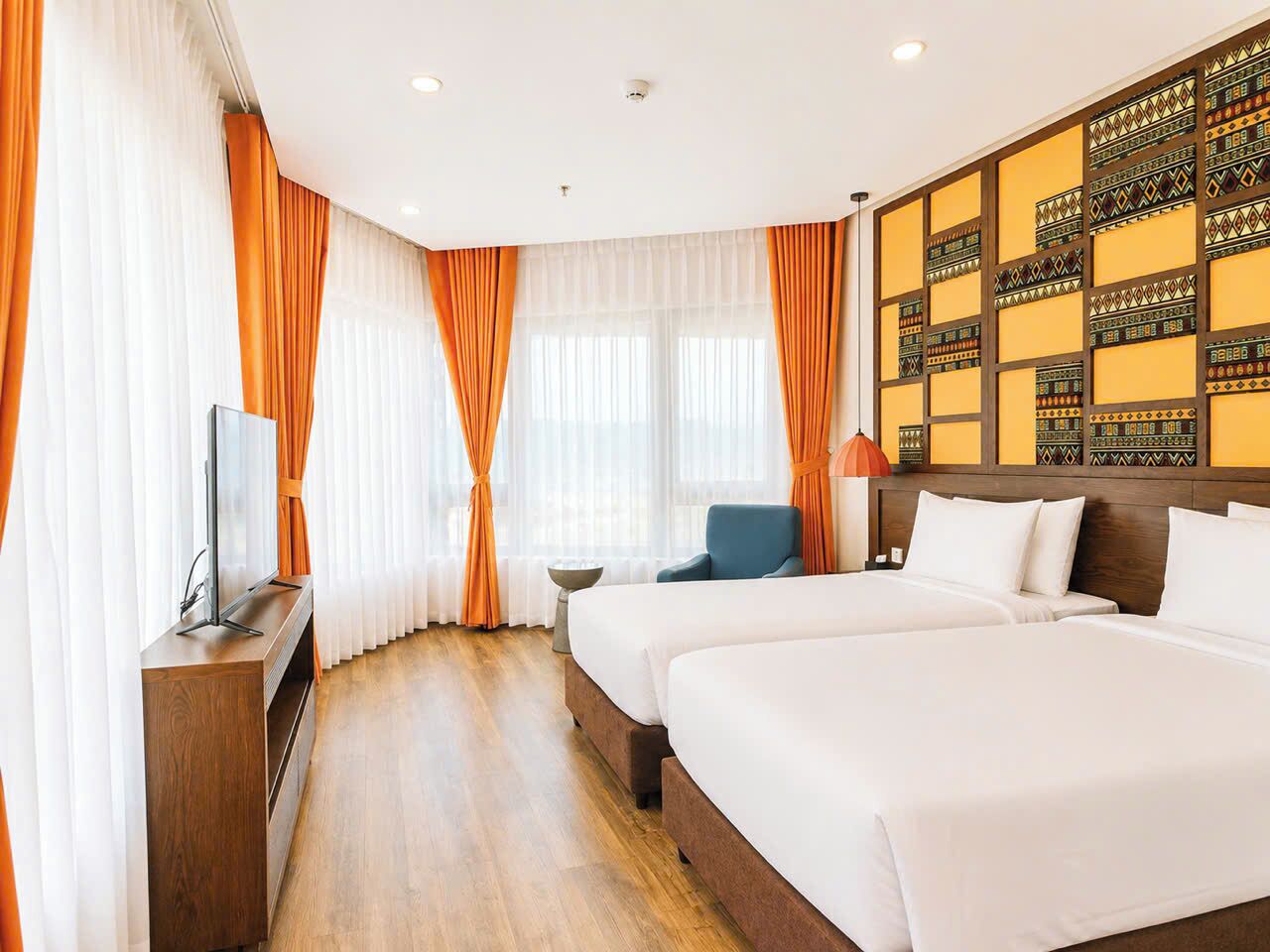 Une chambre d’hôtel avec deux lits, une télévision et un mur décoré de motifs.