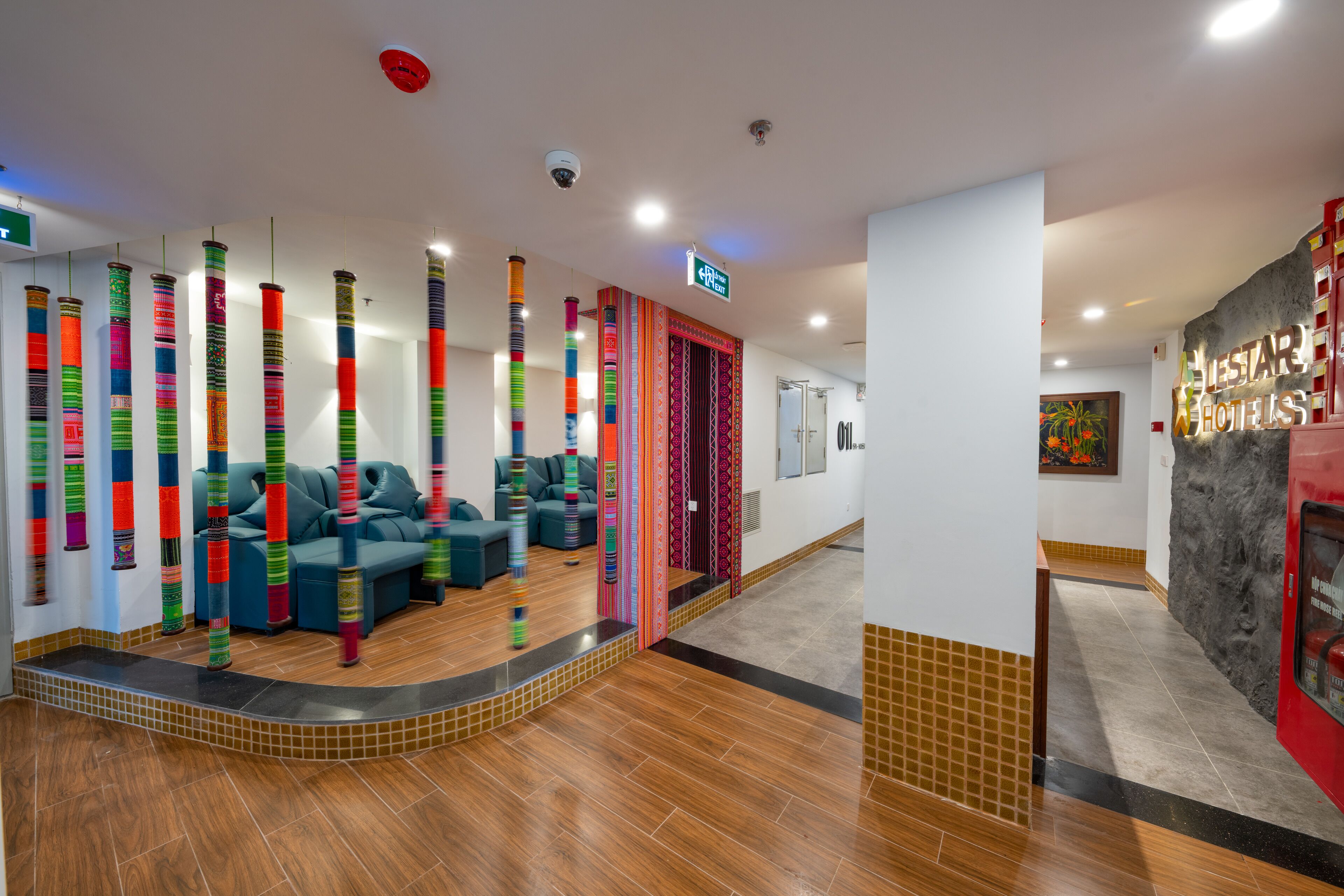 A hotel lobby with a seating area, a reception desk, and a staircase leading to the upper floor.