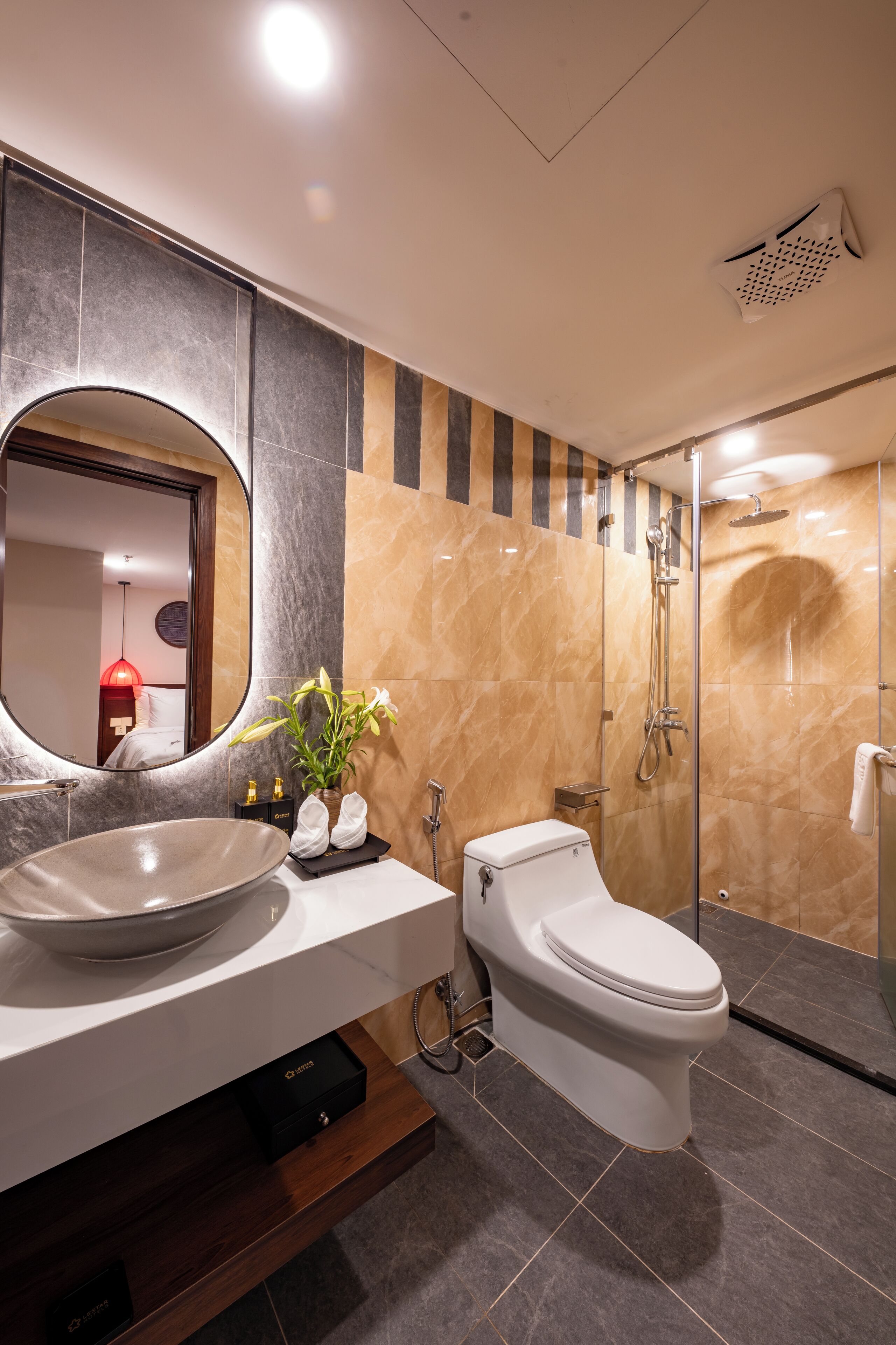 A modern bathroom with a large oval sink, a toilet, and a glass-enclosed shower.