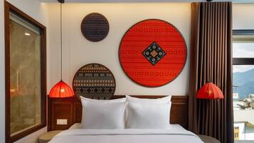 A hotel room with a bed, two red pendant lights, and three decorative wall plates.