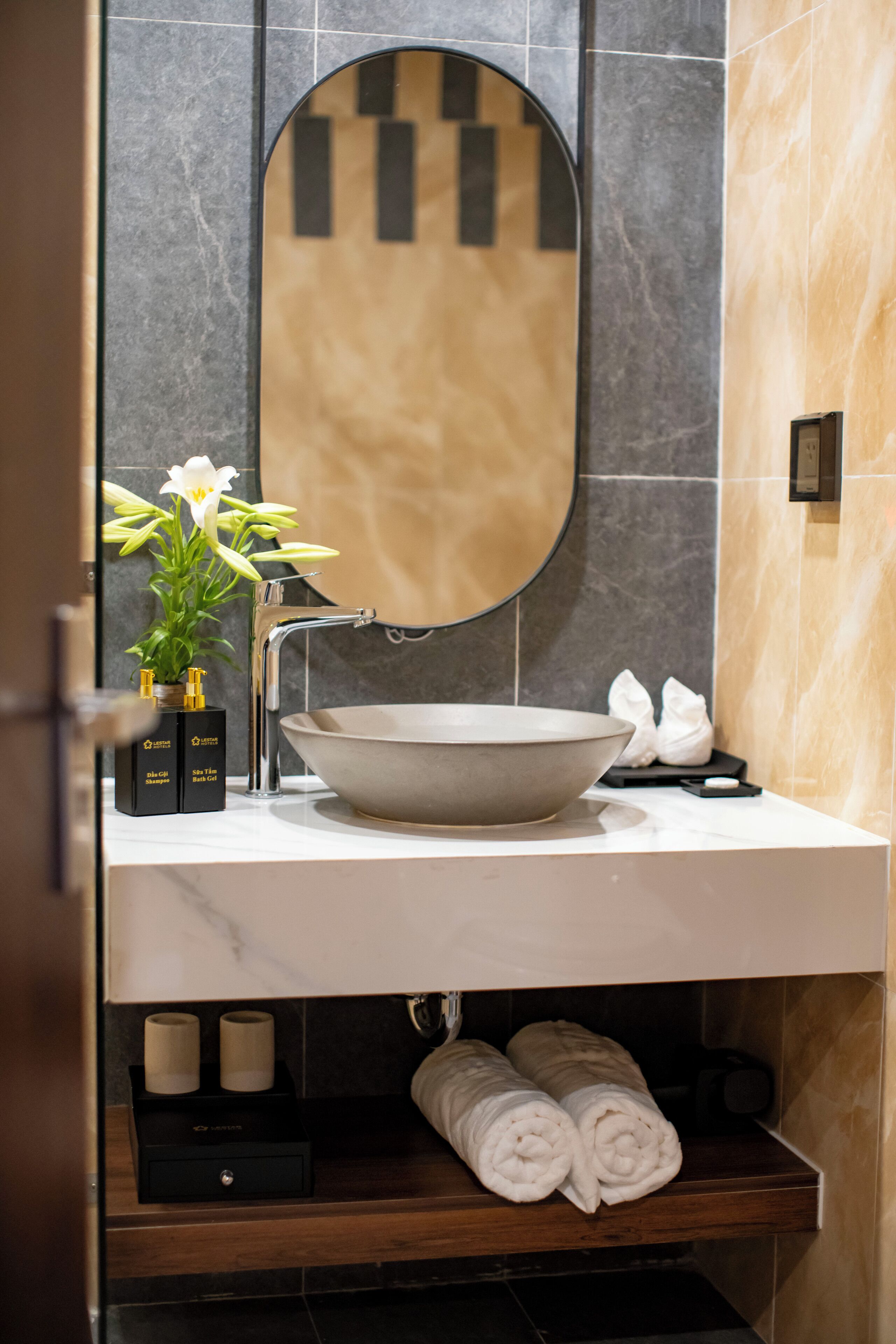Un baño moderno con un espejo ovalado grande, un lavabo tipo cuenco y una pequeña planta en maceta.