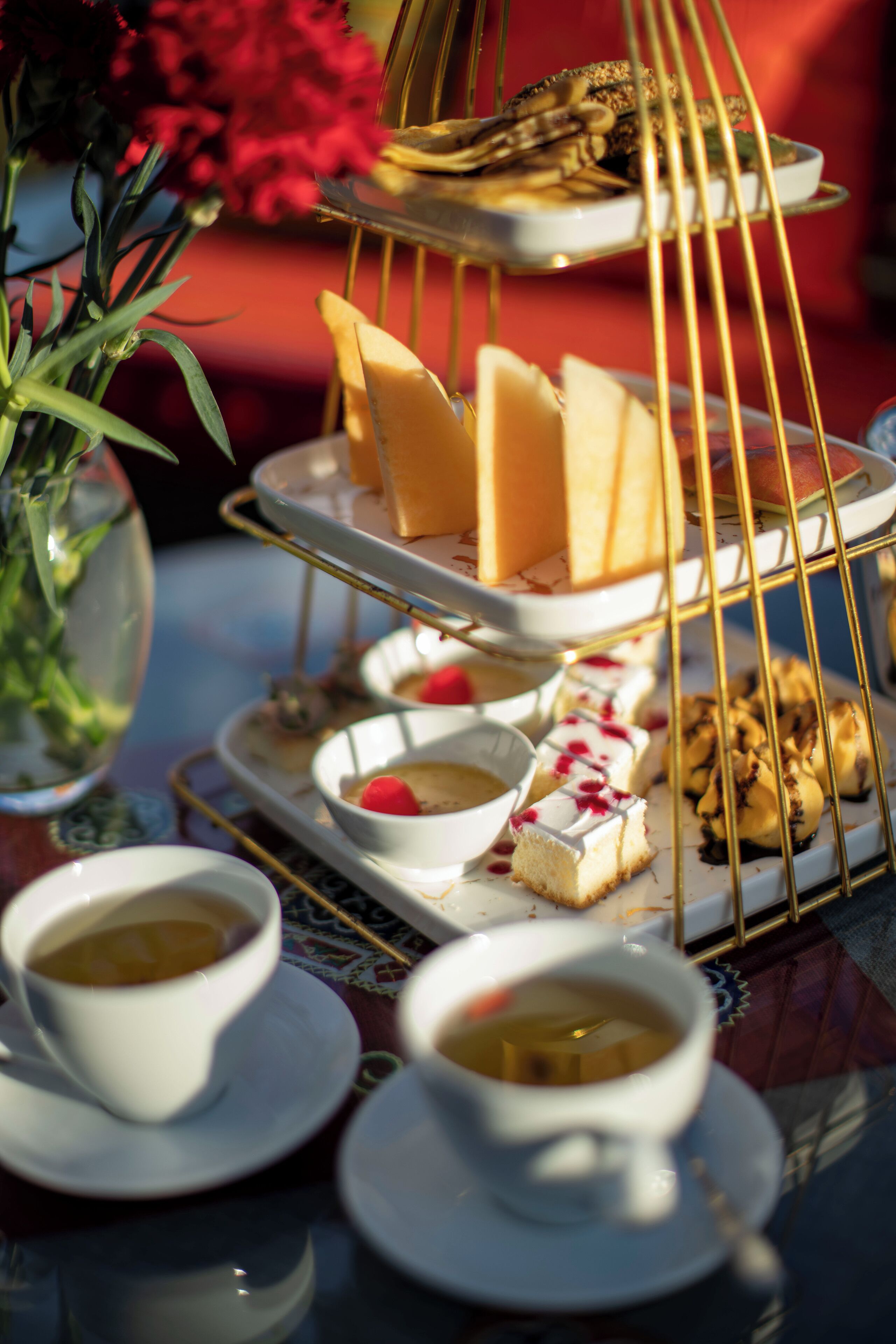 Un expositor escalonado con varios pasteles y una vajilla de té.