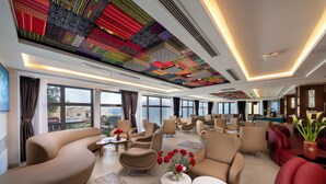 Amplia sala de estar con diversas opciones de asientos, ventanas grandes que ofrecen vistas y un techo con baldosas decorativas.