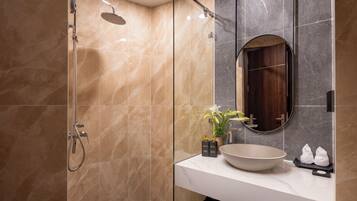 A modern bathroom with a glass-enclosed shower, a large sink, and a mirror.