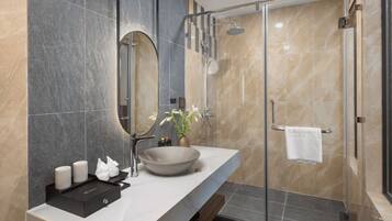 A modern bathroom with a large mirror, a round sink, and a glass-enclosed shower.