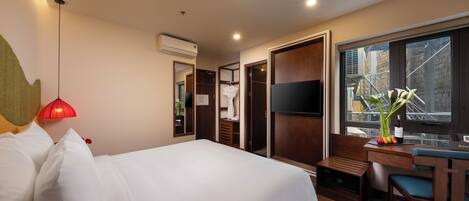 Habitación de hotel con cama, escritorio, silla, televisor y ventana con vista al exterior.