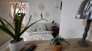 Une chambre à coucher avec un lit, une table de chevet, une lampe et une plante en pot.