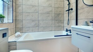 Un baño moderno con bañera, ducha y lavamanos.