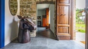 Un pasillo con pared de piedra, puerta de madera y una escultura de caballo.