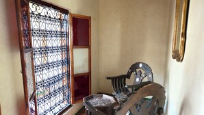 A room with a patterned carpet, a wooden chair, a metal gate, and a framed picture on the wall. - Riad sarsavti (Marrakech)