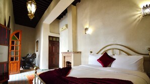 A bedroom with a bed, a wooden door, a fireplace, and a patterned floor. - Riad sarsavti (Marrakech)