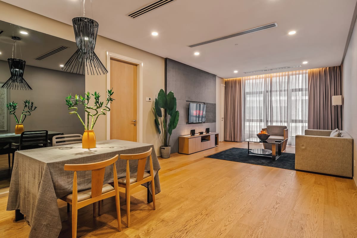 Una sala moderna con comedor, suelo de madera y una planta grande.