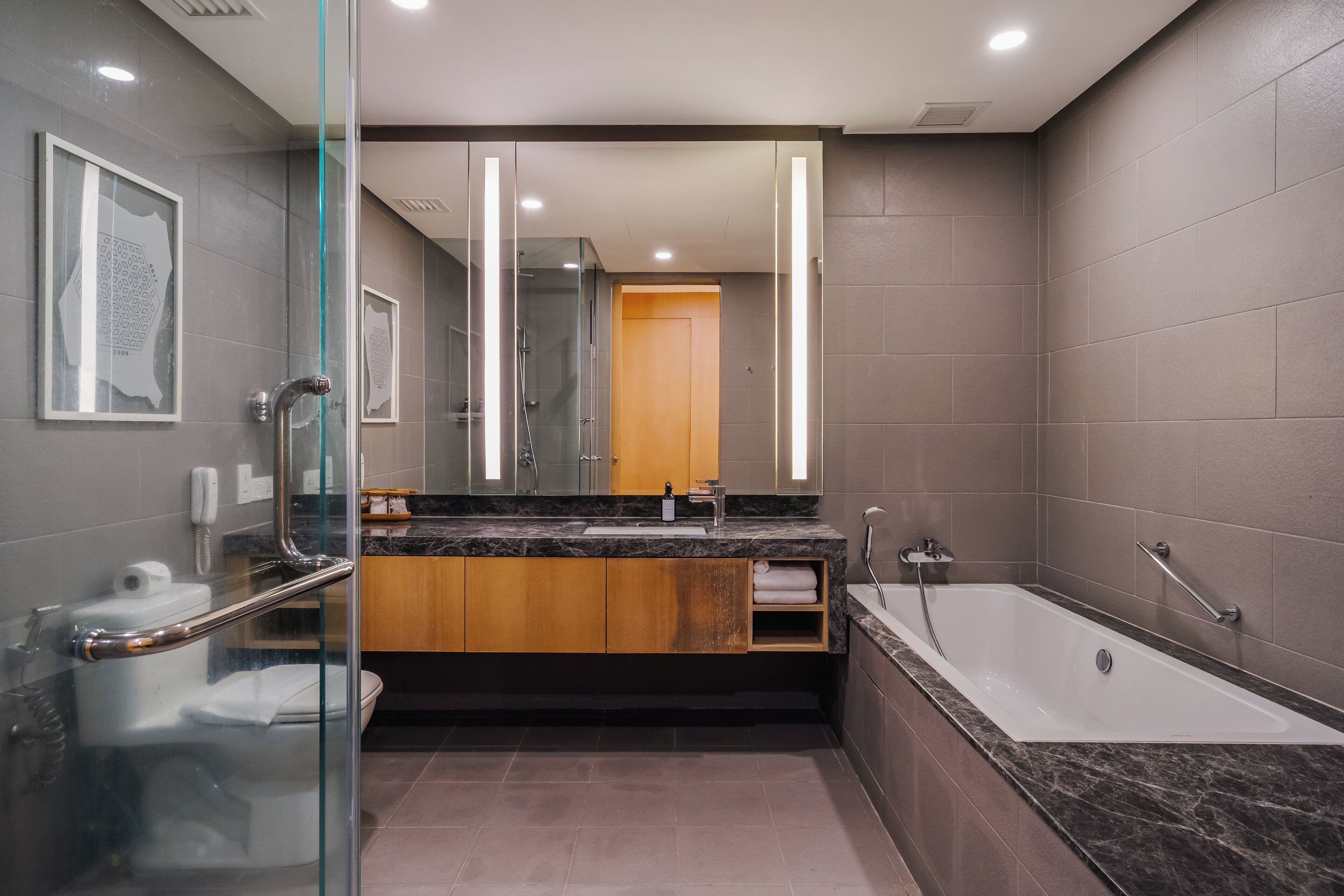 A modern bathroom with a glass shower enclosure, a large mirror, a bathtub, and a vanity with a sink.