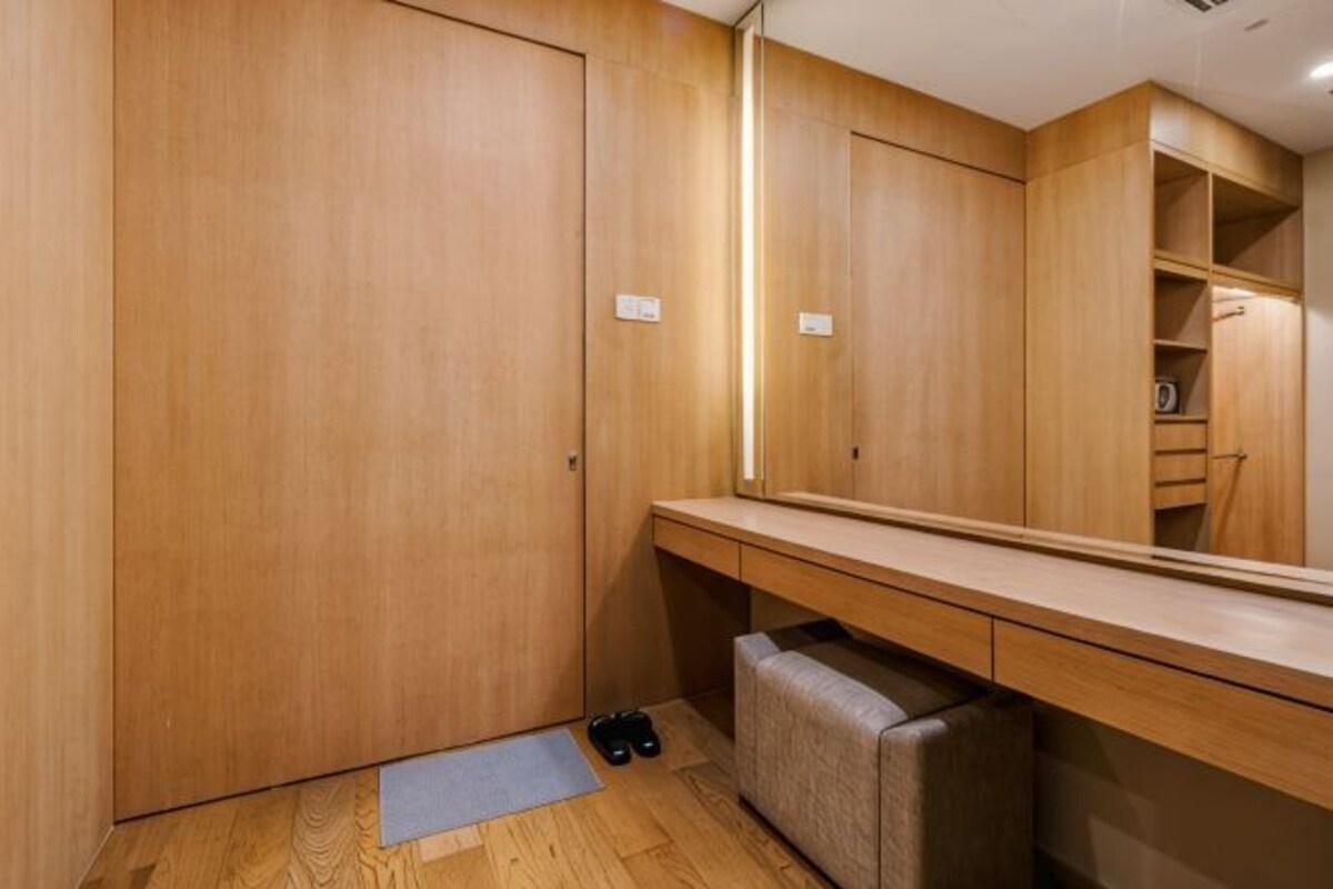 Un armario de madera, un espejo, un banco y una alfombra pequeña en una habitación.