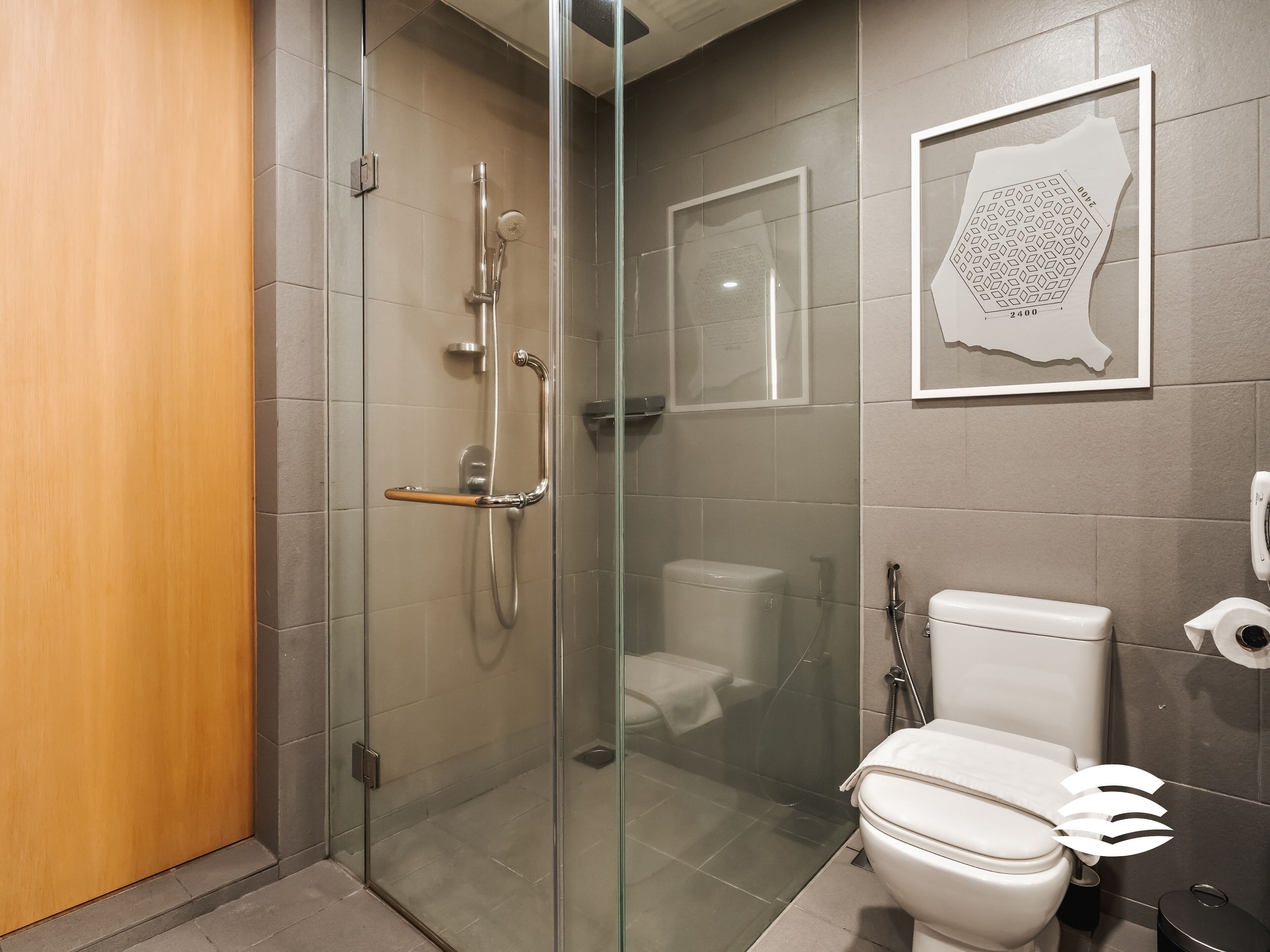 A modern bathroom with a glass-enclosed shower, a toilet, and a sink.