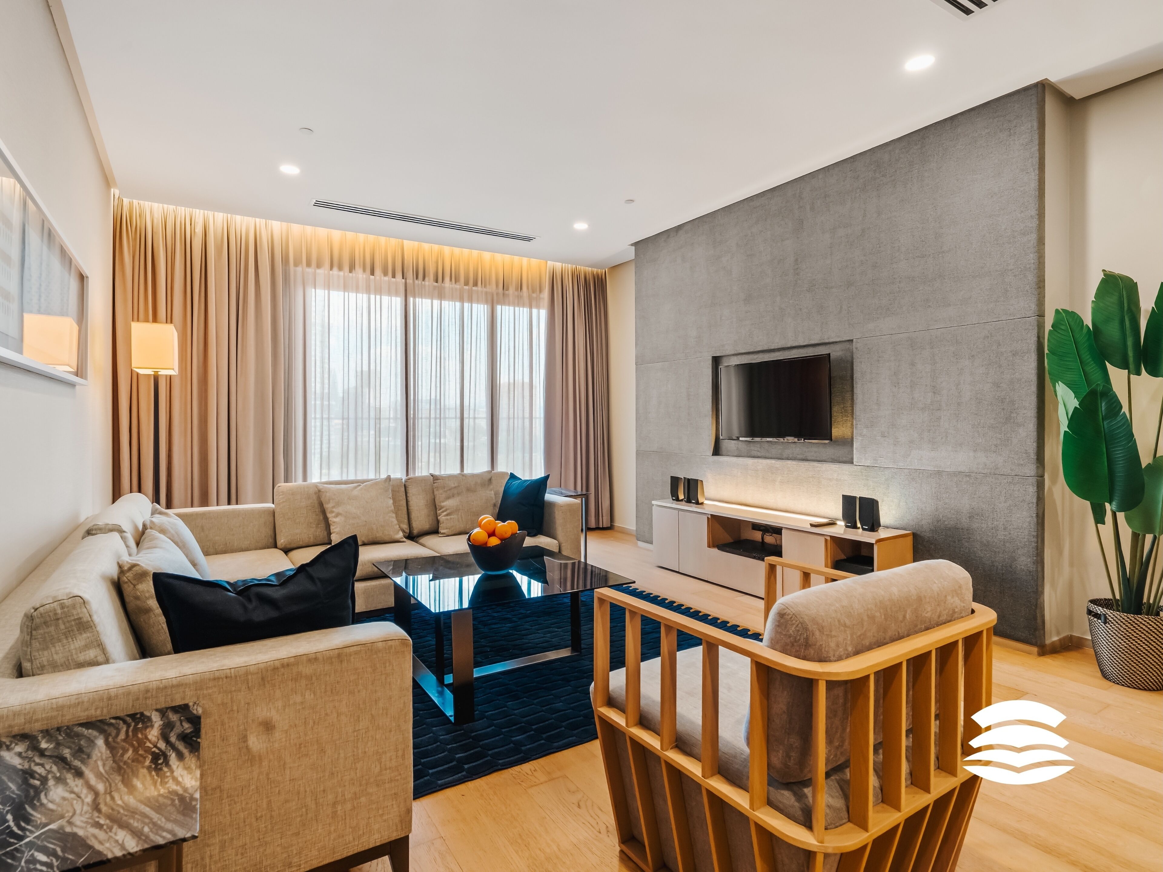 Un salon moderne avec un canapé, une table basse et un téléviseur fixé au mur, qui est de couleur grise.
