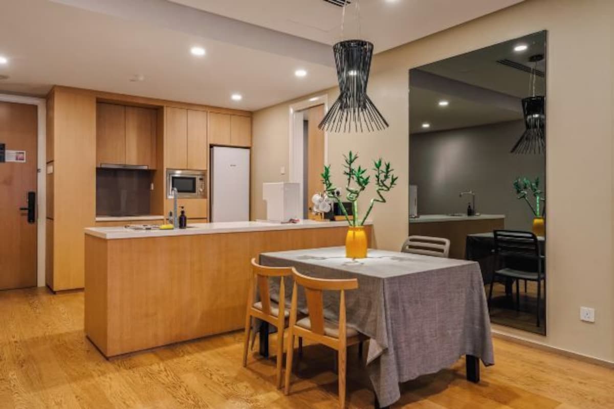 A modern kitchen with wooden cabinets, a central island, and a dining area with a table and chairs.