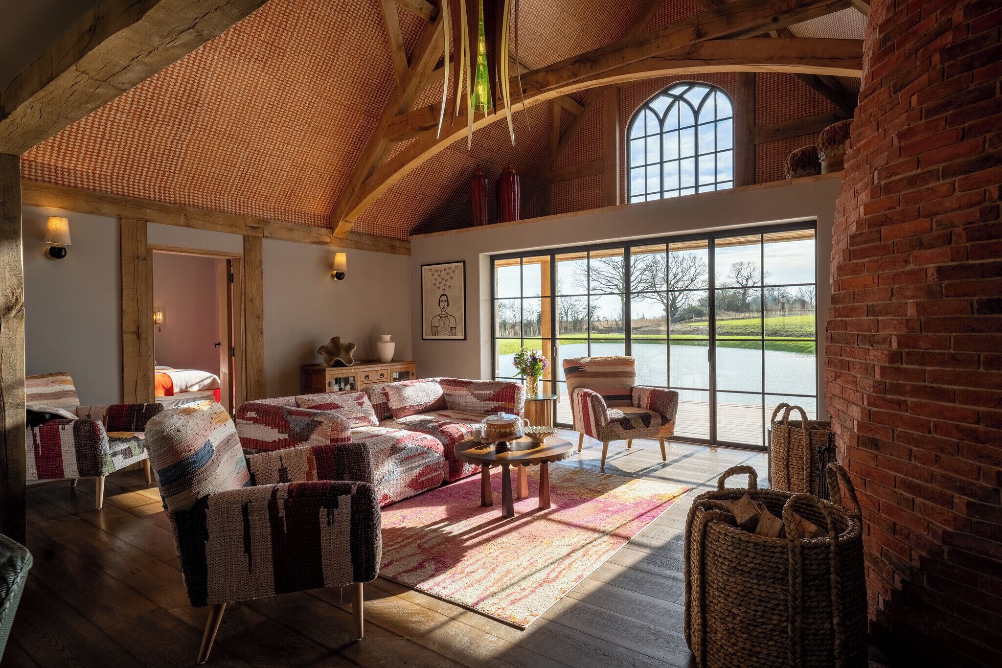 Un salón acogedor con un ventanal grande, vigas de madera y decoración rústica.
