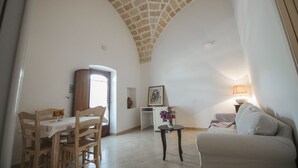 Ein Essbereich mit Tisch und Stühlen, ein kleiner Tisch mit einer Vase, eine Couch und eine Lampe.