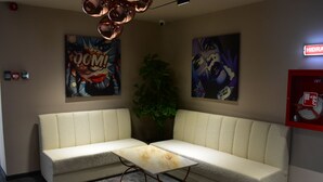 Una habitación con un sofá beige, una mesita y dos carteles en la pared.