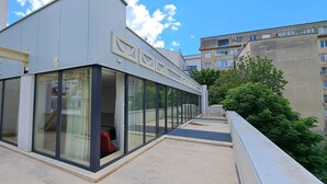 Un edificio moderno con grandes ventanales y una terraza con techo plano.