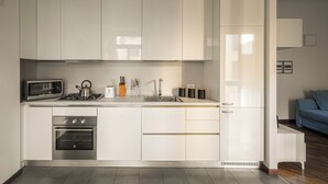 Uma cozinha moderna com armários brancos, forno embutido, micro-ondas e pia.