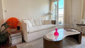 A modern living room with a white sofa, a coffee table, and a bookshelf. - L'appartement Colombier (Paris)
