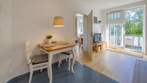 Ein zeitgemäßer Essbereich mit Holztisch, weißen Stühlen und einer Pendelleuchte.