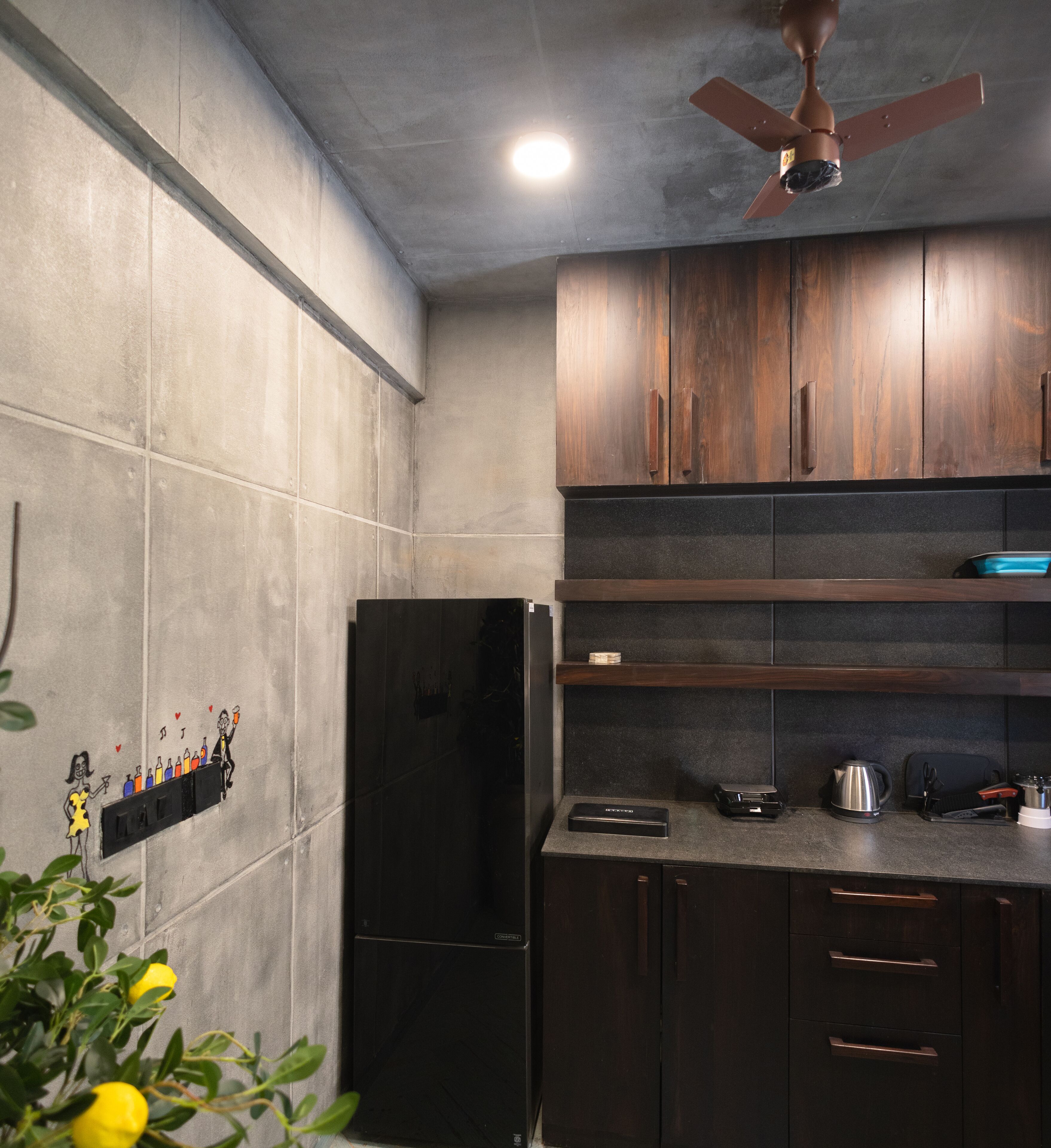 A kitchen with dark wooden cabinets, a black refrigerator, and a ceiling fan.