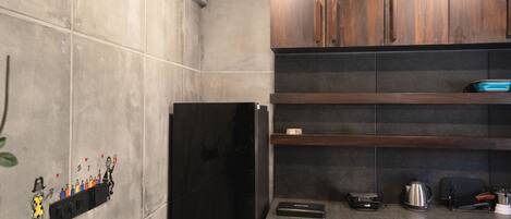 A kitchen with dark wooden cabinets, a black refrigerator, and a ceiling fan.