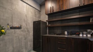 Eine Küche mit dunklen Holzausziehtüren, einem schwarzen Kühlschrank und verschiedenen Geräten auf der Arbeitsfläche.