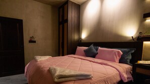 Ein Schlafzimmer mit einem Bett, Kissen, einem Nachttisch, einer Lampe und einer Tür.