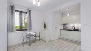 A modern kitchen with white cabinets, a black countertop, and a window with curtains. - Apartamenty Sun & Snow Zasypane Mazury (gmina Malkinia Gorna)