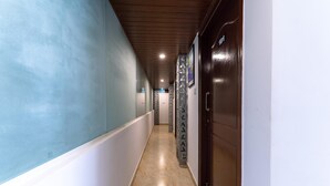 A hallway with a marble floor, wooden ceiling, and a door with a number. - Treebo Emirates Suites Indiranagar (Bangalore)