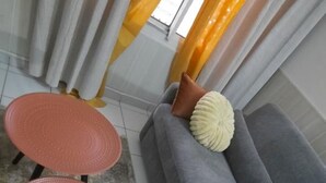 A living room with a grey sofa, two red woven stools, and a yellow throw pillow.