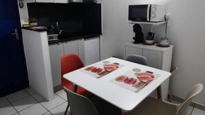 A compact kitchen with a microwave, stove, and a flat-screen TV.