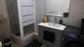 Chuveiro, toalhas de banho, sabonete, papel higiênico