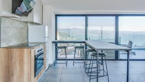 Eine moderne Küche mit einer großen Kochinsel, Barhocker und Blick auf die Stadt.