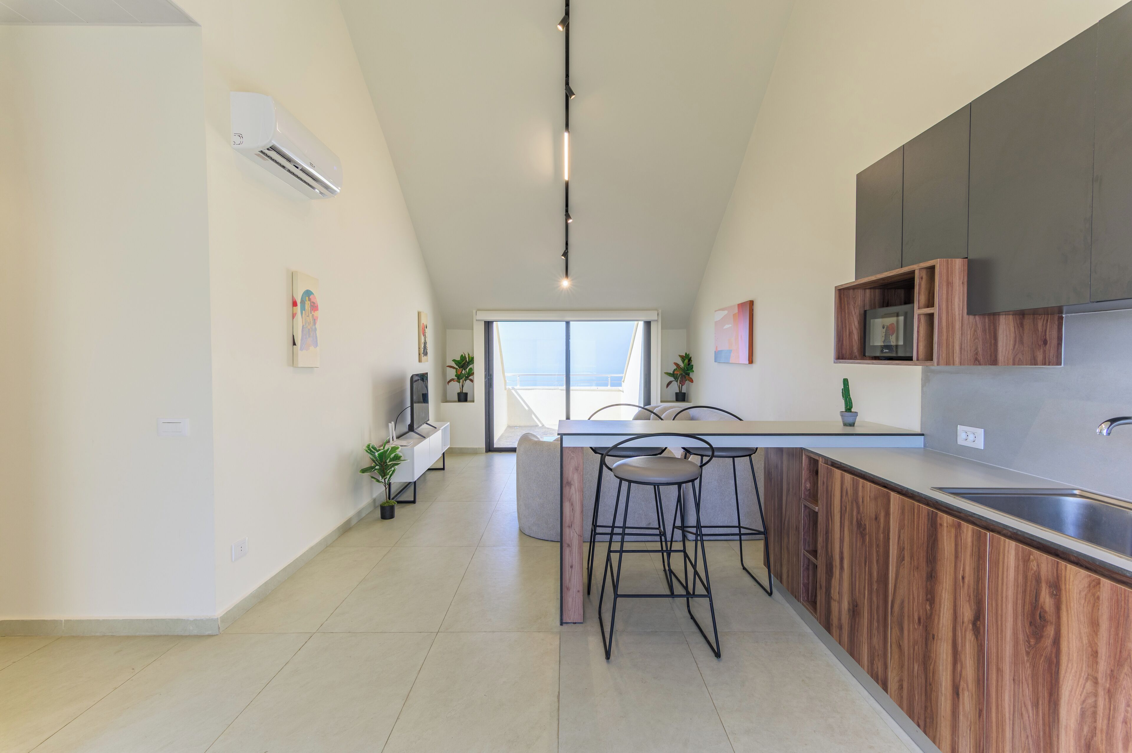 Una cocina moderna con una isla central, taburetes de bar y un horno empotrado.